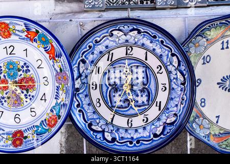 Three blue and white plates with clocks on them. The clocks are set at different times. The plates are arranged in a row. City of Puebla, Mexico, craf Stock Photo