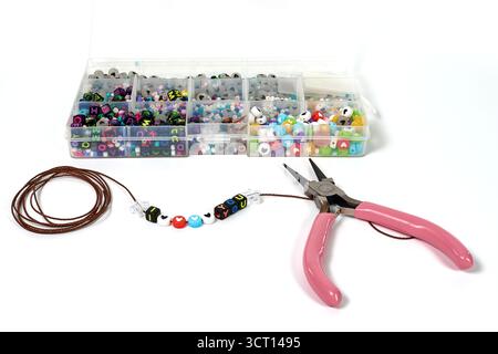 A clean and organized layout of a DIY craft project. Making a handmade 'I Love You' bracelet with alphabet beads, string, and pliers, isolated on whit Stock Photo