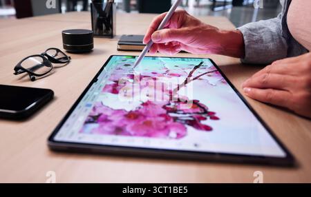 Creative Designer Editing Digital Artwork On Tablet At Desk Stock Photo