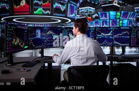 Senior Trader Analyzing Stock Market Data On Multiple Computer Screens. Stock Photo
