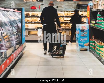 Lombardy, Italy - October 1st 2025 Man and woman grocery shopping in an Italian Aldi discount supermarket browsing shelves and bakery items Stock Photo