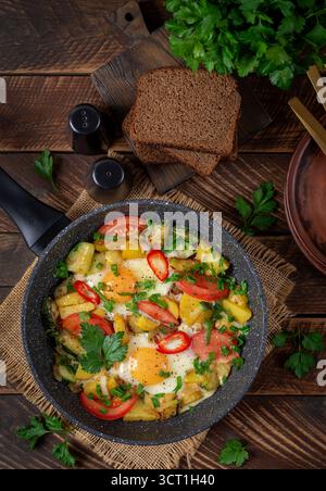 Fried eggs and potatoes, tomatoes, zucchini  and chili peppers in a rustic style.  Overhead Stock Photo