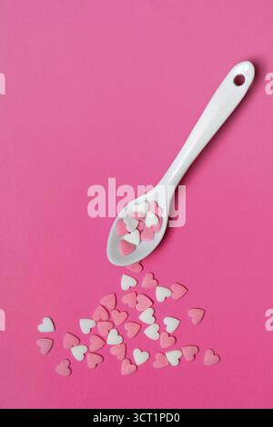 Sugar hearts with spoon on pink background Stock Photo