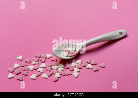 Sugar hearts with spoon on pink background Stock Photo
