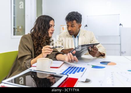 Diverse business colleagues discussing financial data and charts during an office meeting, collaborating on a project and analyzing performance figure Stock Photo