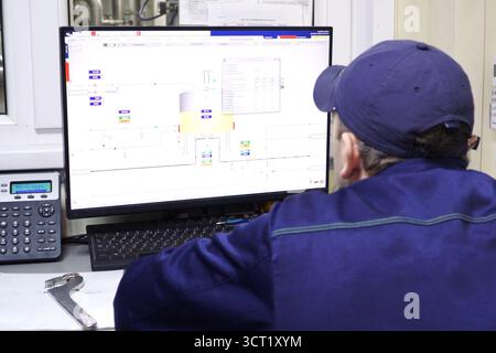 Worker behind the monitor of the brewery equipment control panel. Stock Photo