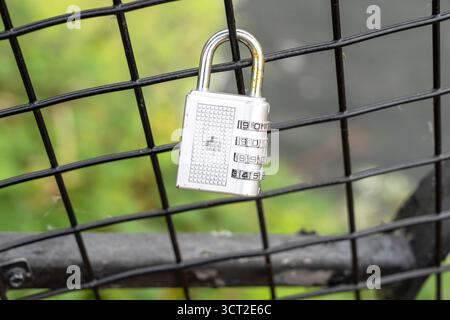 Combination padlock hanging on wire fence Stock Photo