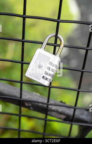 Combination padlock hanging on wire fence Stock Photo