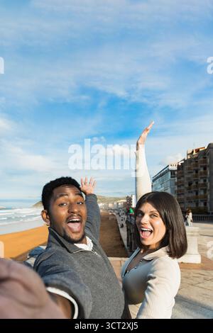 Excited couple taking a joyful selfie at the beach. Lifestyle concept. Stock Photo