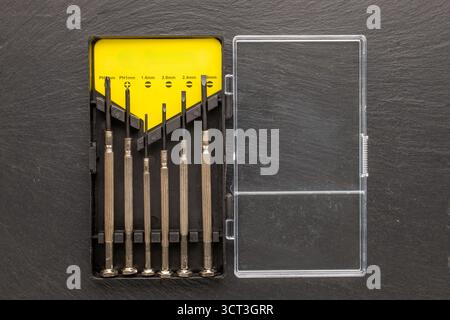Set of steel screwdrivers for precision mechanics on slate stone, macro, top view. Stock Photo