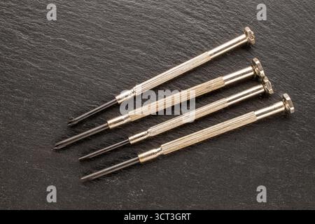 Set of steel screwdrivers for precision mechanics on slate stone, macro, top view. Stock Photo