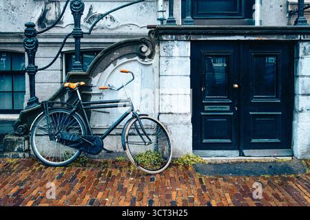 A bicycle leaning against a building in Amsterdam on a rainy day Stock Photo