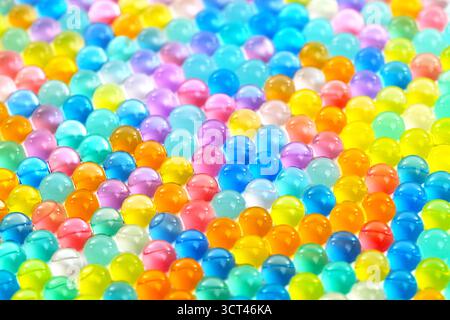 A colorful array of small, clear, and shiny spheres. The spheres are of various colors, including blue, green, yellow, and orange. Concept of vibrancy Stock Photo