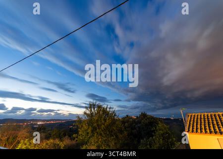Breathtaking long exposure captures the dramatic motion of clouds sweeping over a tranquil landscape at twilight. The deep blue hour sky contrasts wit Stock Photo