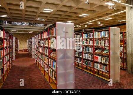 Interior view of the modern public library in Bruges featuring rows of colorful bookshelves and concrete architectural design Stock Photo