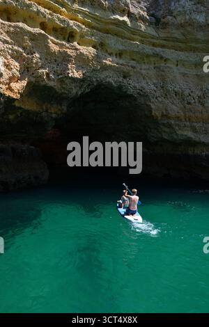 Paddle boarders explore one of the many caves along the Algarve coastline in Portugal. Stock Photo