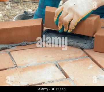 A man builds a brick wall. Brick put on the solution. Construction of a brick house. Stock Photo