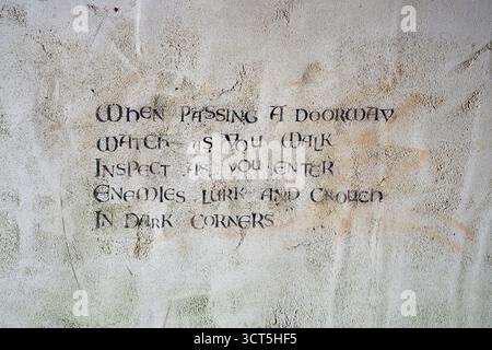 Historic survival advice etched on textured stone, teaching soldiers situational awareness in fortified spaces. Stock Photo