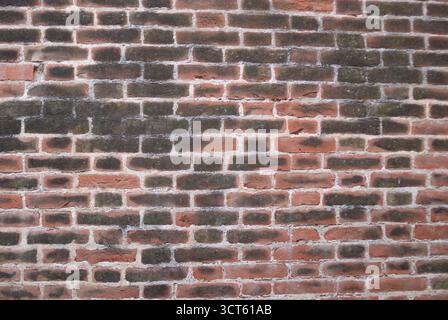 A weathered and aged red brick wall texture displaying a subtle patina of time and natural elements Stock Photo