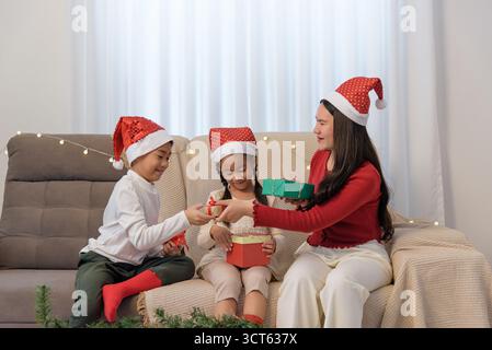 Christmas family gathers at home, parent and children exchange holiday gifts, happy children open Stock Photo
