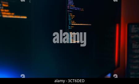 Dark monitor code programming cyber workspace with colorful syntax highlighting and LED lighting. Ideal representation of a modern tech developer envi Stock Photo