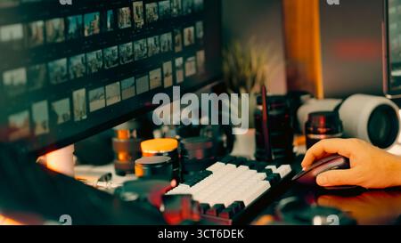 Photo editing workspace creative studio technology setup. Close-up of photographer’s hand on mouse with dual monitor screens, camera lenses and access Stock Photo