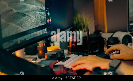 Photo editing color grading monitor workspace studio. Photographer adjusting image tones using professional software, visible ocean view on screen, cr Stock Photo
