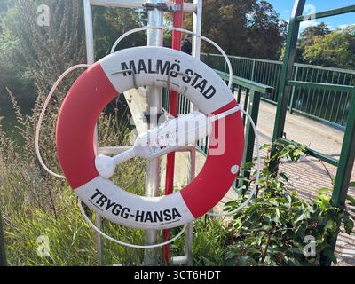 Emergency lifebuoy rings on stands positioned beside water in Sweden and Denmark, including orange flotation devices with attached lines for throwing Stock Photo
