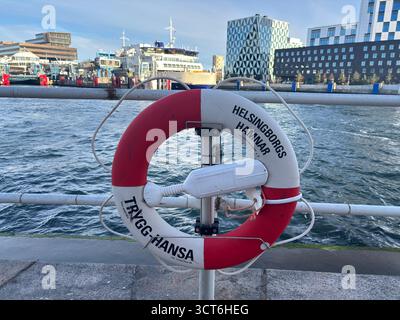Emergency lifebuoy rings on stands positioned beside water in Sweden and Denmark, including orange flotation devices with attached lines for throwing Stock Photo