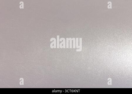 The background is a smooth gray textured surface with barely noticeable reflection of light. Smooth tone and fine grain. Stock Photo
