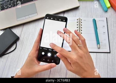 Woman's hands touching a blank cell phone screen in an office environment Stock Photo