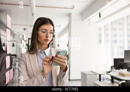 Serious busy project manager using online business application on smartphone Stock Photo