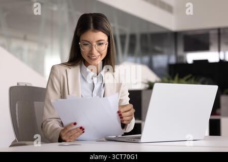 Positive business leader woman in glasses checking paper financial reports Stock Photo