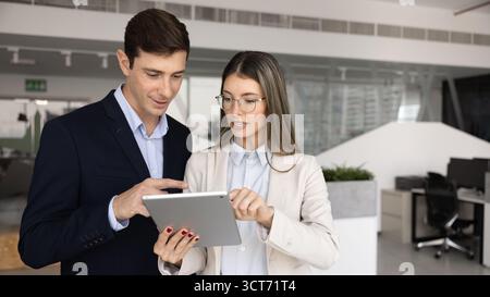 Couple of young Hispanic coworkers using tablet pc together Stock Photo