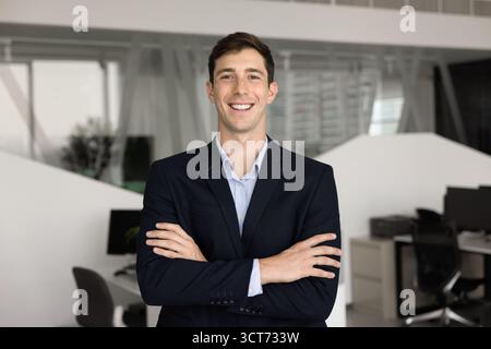 Positive young professional man posing on office with hands folded Stock Photo