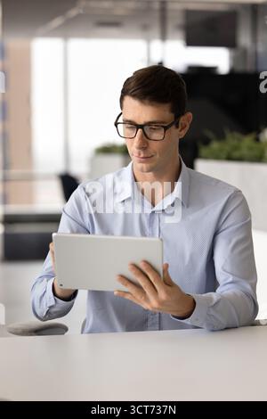 Serious smart Latin project manager man using professional software Stock Photo