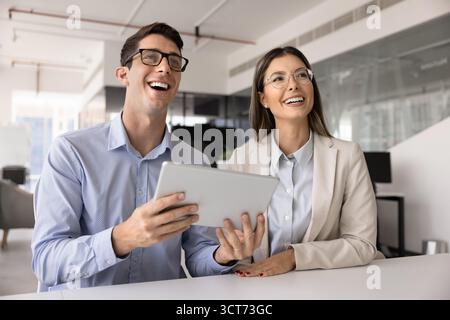 Couple of happy young Latin businesspeople using tablet for teamwork Stock Photo
