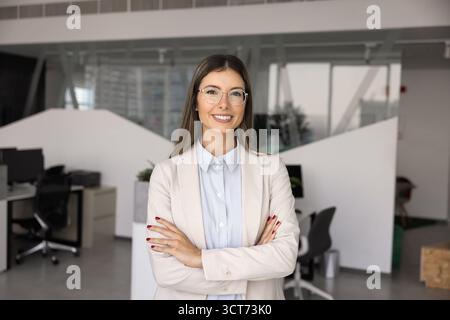 Happy beautiful young Hispanic businesswoman posing with hands crossed Stock Photo