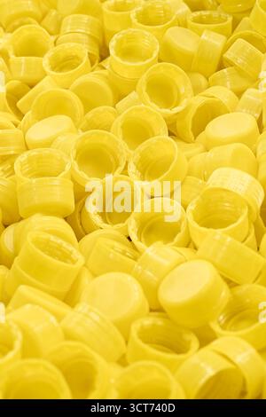 Lots of yellow plastic bottle caps, close up shot, abstract yellow background Stock Photo