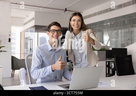 Two cheerful successful company workers posing at laptop Stock Photo