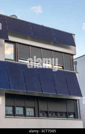 Residential building with continuous window fronts and solar panels on the facade Stock Photo