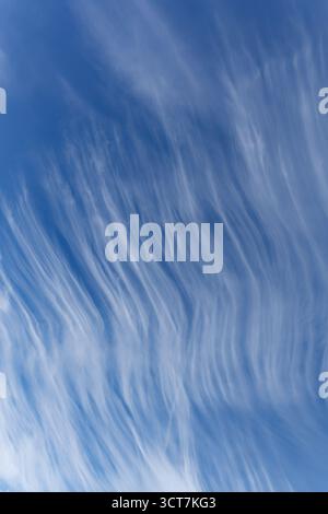 Wavy line high cloud formation against a blue sky forming abstract shapes Stock Photo