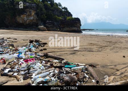 Large pile of discarded plastic bottles and trash polluting a remote beach. Stock Photo
