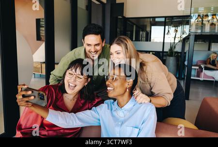 Group of diverse young adults enjoying teamwork and camaraderie while smiling and taking a selfie. Stock Photo
