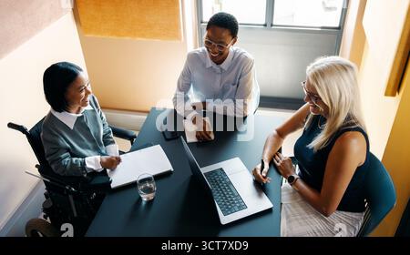 A diverse group of professionals, including a wheelchair user, having a productive meeting in an office. Stock Photo