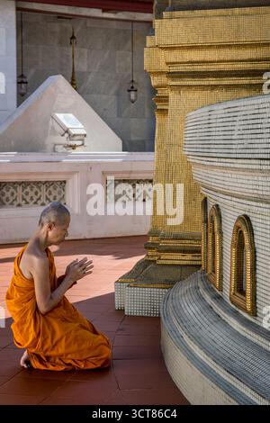 A Thai monk praying in front of a stupa, Bangkok, Thailand Stock Photo