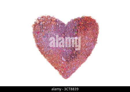 A multicolored pink heart made from scattered eyeshadow powder isolated on white background. Stock Photo