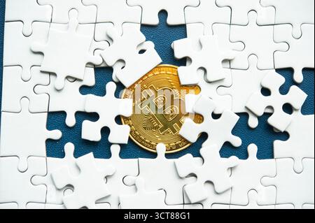 Bitcoin coin surrounded by white puzzle pieces symbolizing complexity, integration, and connection of blockchain technology Stock Photo