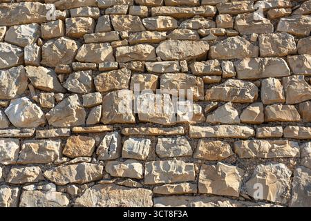 A close-up view of a stacked gray stone wall built from irregularly shaped rocks. Natural texture and rugged craft convey rustic charm, durability, an Stock Photo