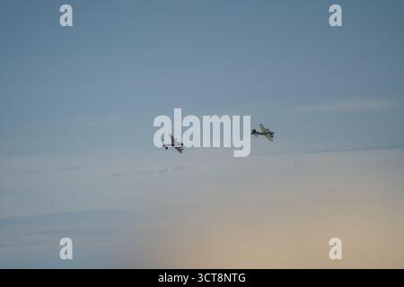 Two vintage military aircraft flying in formation against cloudy sky at Duxford airshow Stock Photo